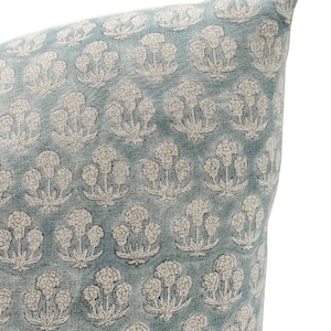 May include: A light blue pillow with a white floral pattern. The pillow is made of a soft, textured fabric.