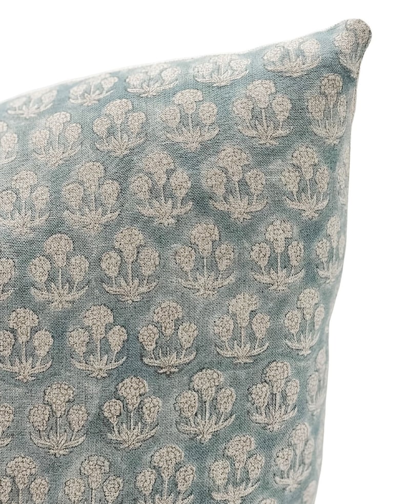 May include: A light blue pillow with a white floral pattern. The pillow is made of a soft, textured fabric.