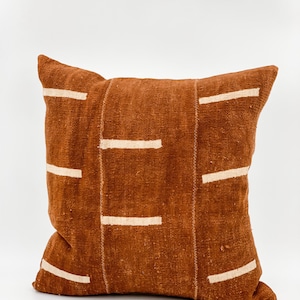 May include: A brown throw pillow with a white geometric pattern. The pillow is made of a soft, textured fabric.