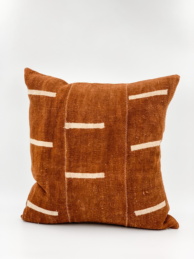 May include: A brown throw pillow with a white geometric pattern. The pillow is made of a soft, textured fabric.