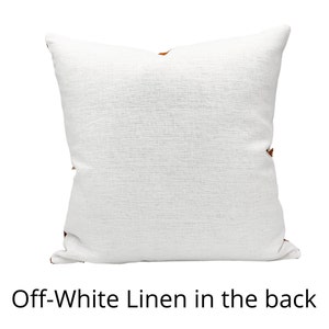 Puede incluir: Almohada de lino de color blanco roto con una textura sutil. La parte posterior de la almohada es visible, mostrando la tela de lino.