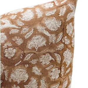May include: A brown throw pillow with a white floral pattern. The pillow is made of a soft, textured fabric.