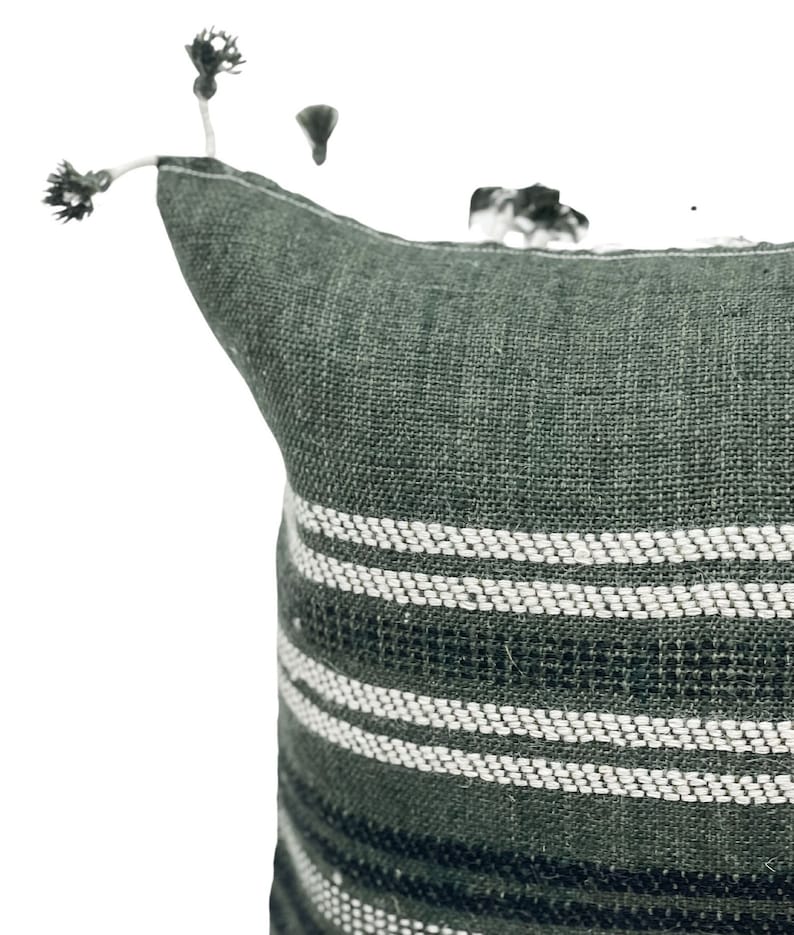 Pode incluir: Uma almofada decorativa verde escuro com listras horizontais brancas. A almofada tem um tecido texturizado e &eacute; adornada com pequenas borlas no canto. Esta almofada de acento &eacute; adequada para uma cama ou sof&aacute;.
