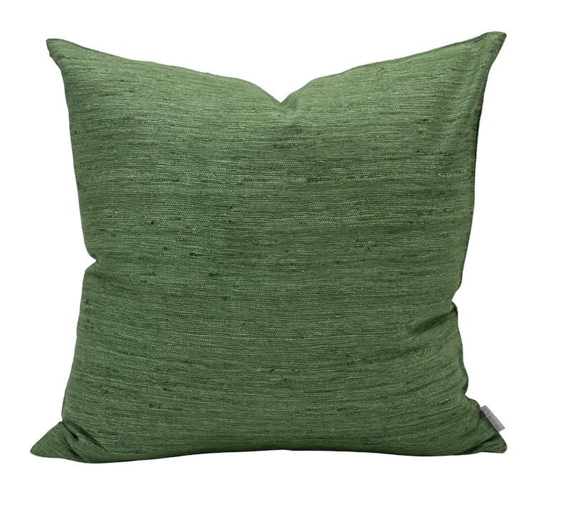 Puede incluir: Una almohada cuadrada verde con tejido texturizado.