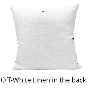 Pu&ograve; includere: Cuscino in lino bianco sporco con superficie strutturata. Il cuscino ha una forma quadrata ed &egrave; decorato con piccoli accenti decorativi marroni sugli angoli. Il testo "Off-White Linen in the back" &egrave; visualizzato in basso.