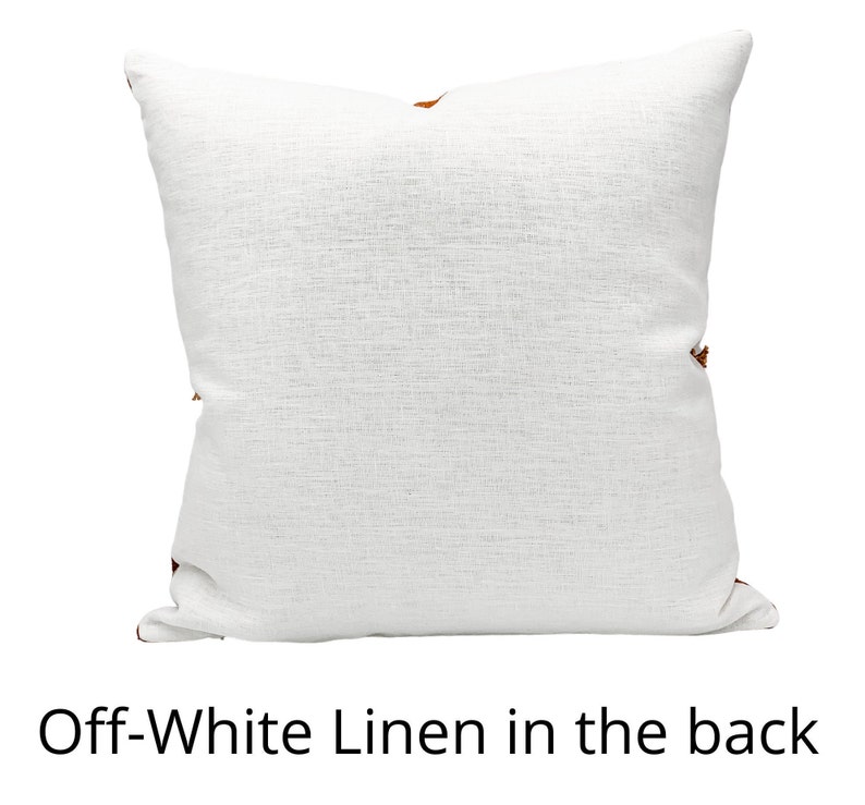 Pu&ograve; includere: Cuscino in lino bianco sporco con superficie strutturata. Il cuscino ha una forma quadrata ed &egrave; decorato con piccoli accenti decorativi marroni sugli angoli. Il testo "Off-White Linen in the back" &egrave; visualizzato in basso.