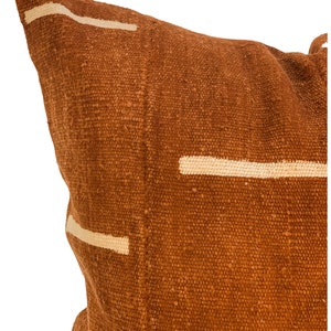 May include: A brown throw pillow with white geometric lines. The pillow is made of a textured fabric.