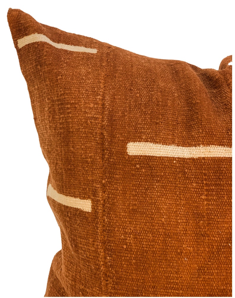 May include: A brown throw pillow with white geometric lines. The pillow is made of a textured fabric.