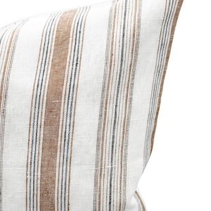 May include: A white pillow cover with brown and black stripes. The pillow cover is made of a linen fabric.