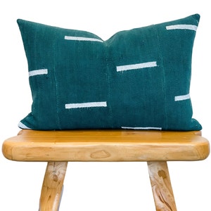 May include: A teal blue throw pillow with white stripes on a wooden stool.