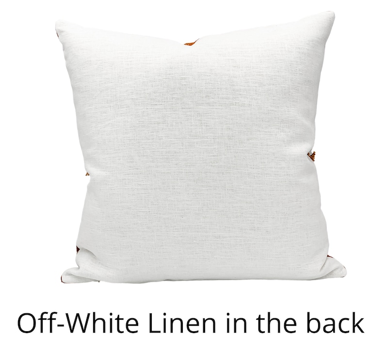 May include: Off-white linen pillow with a textured surface. The pillow has a square shape and features brown accents on the corners. The text "Off-White Linen in the back" is at the bottom of the image.