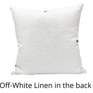 Pu&ograve; includere: Cuscino quadrato in lino bianco sporco con superficie strutturata. Il cuscino ha un accento marrone sugli angoli. Il testo "Off-White Linen in the back" &egrave; in basso nell'immagine.