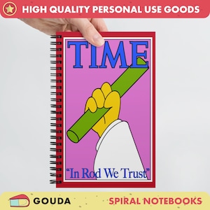 May include: A red spiral notebook with a pink cover featuring a cartoon hand holding a green rod. The cover has the word "TIME" in blue letters and the text "In Rod We Trust" in black letters.