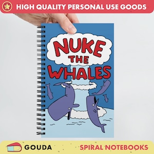 May include: A blue spiral notebook with a cartoon illustration of whales being nuked. The text "NUKE THE WHALES" is in red letters.