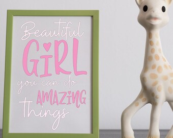 以下が含まれることがあります： 白い背景にピンクの文字で「Beautiful Girl you can do amazing things」と書かれた緑色の額縁。額縁の右側に、暗い表面の上に白いキリンの玩具が置かれている。