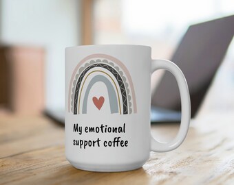 May include: White ceramic mug with a rainbow design and a red heart in the center. The text "My emotional support coffee" is printed below the rainbow.