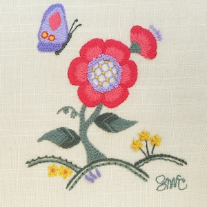 Peut inclure: Broderie représentant une fleur rouge avec un centre violet et un papillon violet, avec des feuilles vertes et des fleurs jaunes sur un fond beige. Le dessin est signé "Smite".