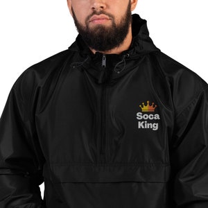 May include: Black windbreaker jacket with a zipper closure and a hood. The jacket has a gold and orange crown graphic with the text "Soca King" embroidered on the front.