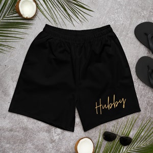 May include: Black athletic shorts with a gold inscription that reads "Hubby".
