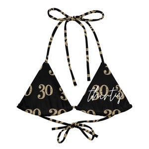 May include: Black bikini top with gold glitter "30" numbers and the word "thirty" in white script.