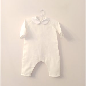 May include: White baby onesie with a peter pan collar. The onesie is made of a soft, lightweight fabric and has long sleeves.