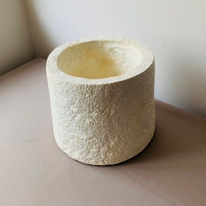 Peut inclure: Un pot cylindrique blanc avec une surface rugueuse et texturée. Le pot est fait d'un matériau léger et a une large ouverture en haut.