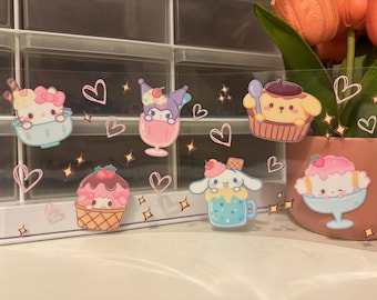Può includere: Una collezione di adesivi colorati con personaggi dei cartoni animati a tema dessert. Gli adesivi includono personaggi in coppe gelato, cupcake e altre prelibatezze, con accenti a forma di cuore e stella. Gli adesivi sono su uno sfondo trasparente.