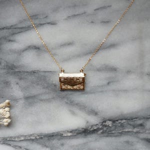 Collar con medallón dorado con forma de sobre o letra