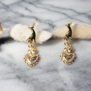Hand met gouden oorbellen heilig hart met boze oog