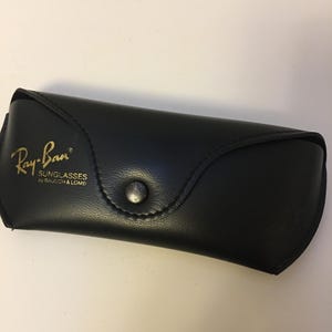 May include: A white ceramic mug with a black handle and the text "But First, Coffee" in a bold, black font. The mug is sitting on a wooden surface. The mug is approximately 4 inches tall.