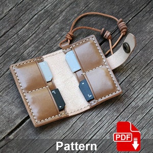 May include: A brown leather case with a strap and multiple slots for memory cards. The case is open and the slots are visible. The case is on a wooden surface. Pattern.