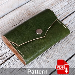 May include: A green leather wallet with a snap closure and a brown leather trim. The wallet is on a wooden surface. Pattern PDF.