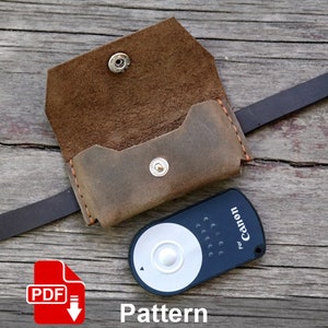 May include: A brown leather case with a strap for a Canon remote control. The case is open and the remote control is visible. The text "For Canon" is printed on the remote control. The image includes the text "Pattern" and a download icon with the text "PDF".