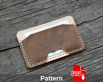 May include: A brown leather card holder with white stitching. The card holder has a flap that folds over the top and a small pocket on the inside. The card holder is on a wooden surface. Pattern PDF.