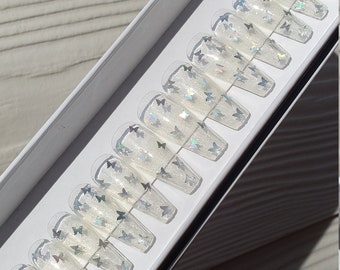 Unghie finte trasparenti a forma di bara con farfalla olografica e glitterata