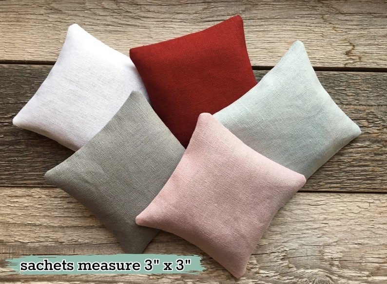 May include: Five fabric sachets in different colors, including white, red, gray, light blue, and pink. The sachets measure 3 inches by 3 inches. "sachets measure 3" x 3"