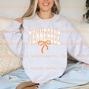May include: A grey sweatshirt with the word "Tennessee" in white letters with an orange bow underneath.