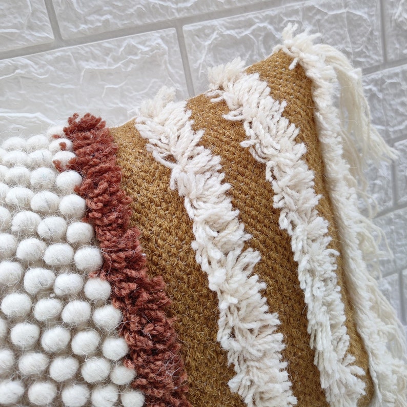 May include: A brown and white throw pillow with a textured, woven design. The pillow has a fringe border and a geometric pattern.