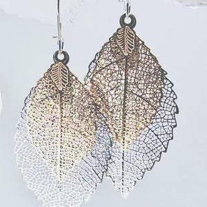 May include: A pair of silver leaf earrings with a layered design. The leaves are gold, silver, and bronze.