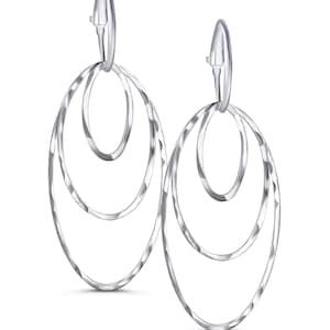 May include: A pair of silver-colored dangle earrings. Each earring features three nested oval hoops with a textured, hammered finish. The earrings have a simple, elegant design and are suspended from a curved hook.