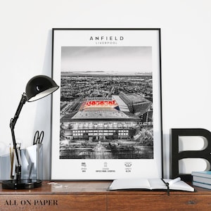Könnte beinhalten: Schwarz-Weiß-Druck des Anfield-Stadions in Liverpool. Das Wort "ANFIELD" steht oben, darunter "LIVERPOOL". Der Name des Stadions leuchtet rot. Enthält das Eröffnungsjahr, den Standort und die Kapazität.