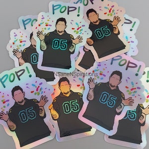 May include: A set of iridescent stickers featuring a cartoon illustration of a person wearing a black jersey with the number "05" on it. The person is surrounded by confetti and the word "POP!" is written on the sticker.