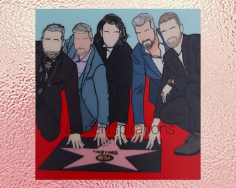 May include: Five men in suits are kneeling on a red carpet in front of a pink star with the word "NSYNC" on it. The men are all smiling and looking at the camera.