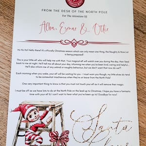 May include: A Christmas letter from the North Pole, addressed to Alba, Esmae & Ottie, signed by Santa Claus. The letter includes a cartoon elf climbing a wooden ladder and a red and white bow. The text reads "Naughty & Nice List is being prepared!"
