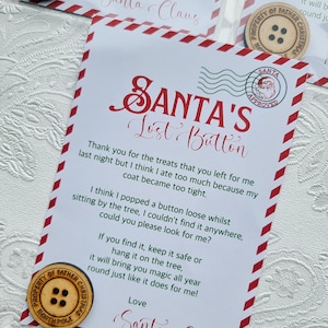 Puede incluir: Una tarjeta blanca con rayas rojas y blancas alrededor de los bordes. La tarjeta tiene un sello verde y blanco con las palabras "Santa's Approved" en él. La tarjeta dice "Santa's Lost Button" en letras verdes y blancas. La tarjeta tiene un mensaje que dice "Gracias por las golosinas que me dejaste anoche, pero creo que comí demasiado porque mi abrigo se ha puesto demasiado apretado. Creo que se me soltó un botón mientras estaba sentado junto al árbol, no pude encontrarlo en ningún lado, ¿podrías buscarlo por mí? Si lo encuentras, guárdalo a buen recaudo o cuélgalo en el árbol, te traerá magia todo el año, como lo hace por mí! Con cariño, Santa Claus". Hay dos botones de madera con las palabras "Property of Father Christmas North Pole" en ellos.