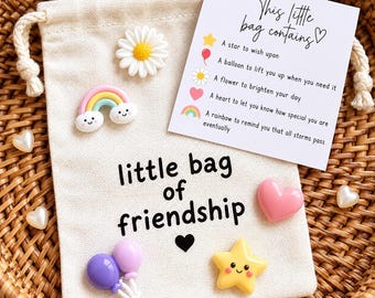 May include: A beige drawstring pouch with the text "little bag of friendship" and a black heart. It features small resin charms: a white daisy, a rainbow, two purple balloons, a pink heart, and a yellow star, plus a card explaining the items.