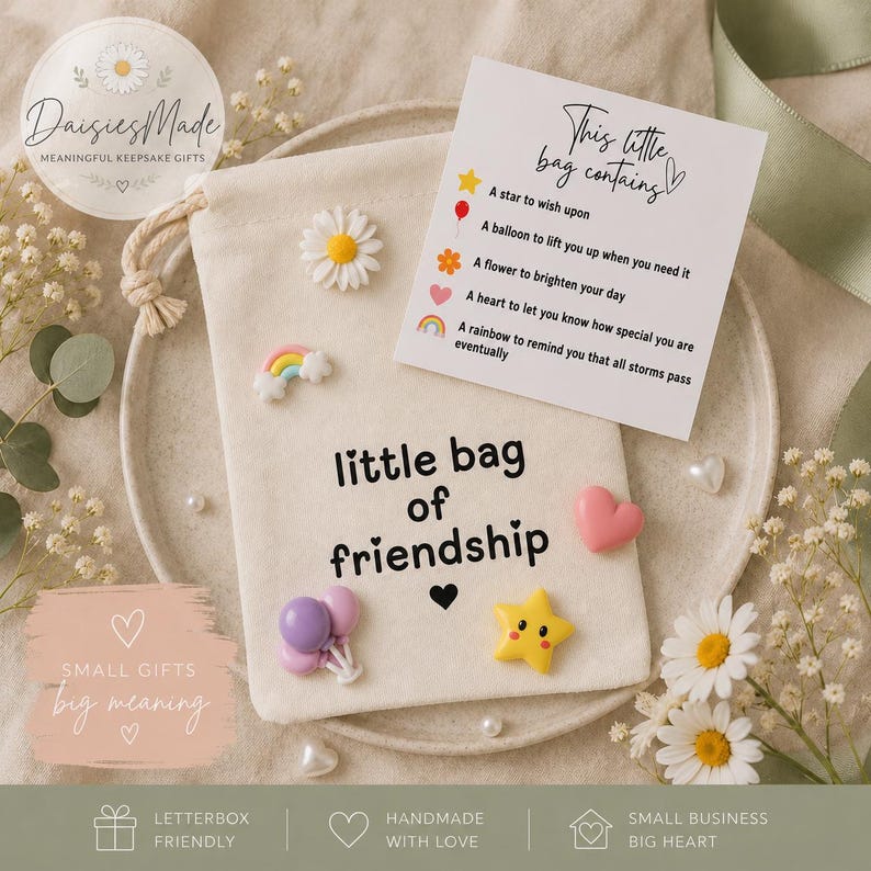 May include: A cream-colored fabric drawstring pouch with the text "little bag of friendship" printed in black. The pouch is decorated with small resin charms including a daisy, a rainbow, two balloons, and a yellow star, plus a card.