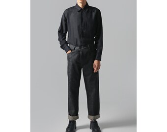 May include: A black long-sleeved shirt with a button-down collar and a black pair of jeans. The jeans have a cuffed hem.