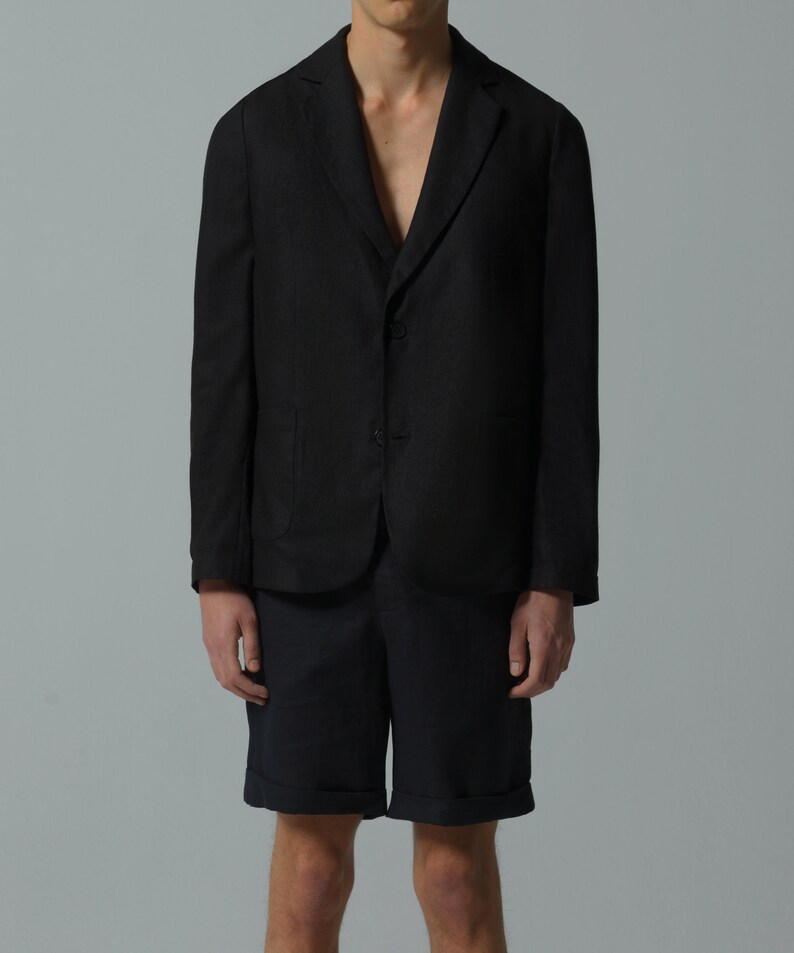 May include: A black linen blazer with a two-button closure and a relaxed fit. The blazer is paired with dark blue linen shorts.