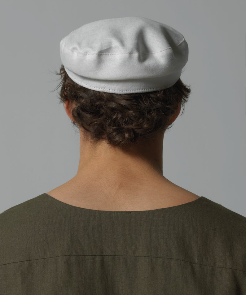May include: A white cotton cap with a rounded crown and a flat brim. The cap is made of a soft, lightweight fabric and has a simple, classic design.